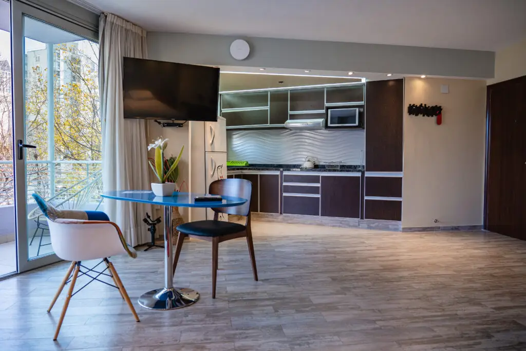 Dining area with glass table, designer chairs and integrated kitchen in the Superior Room with Balcony