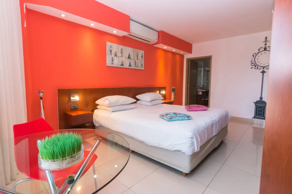 Superior Room with red wall, bed and red designer chairs