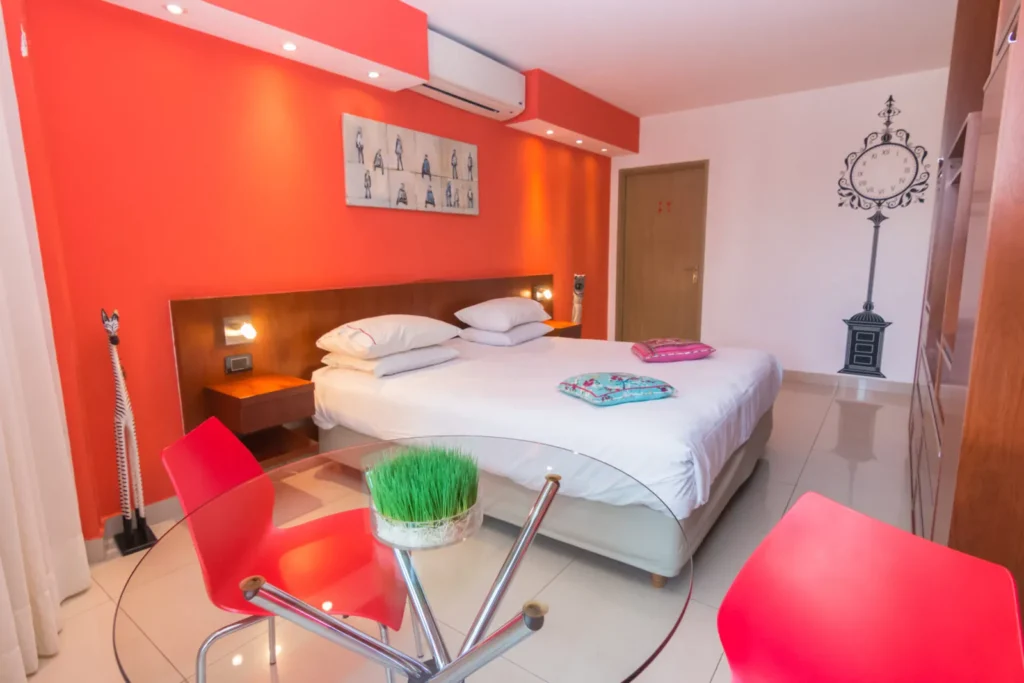 Habitación Superior con pared roja, cama y sillas rojas de diseño