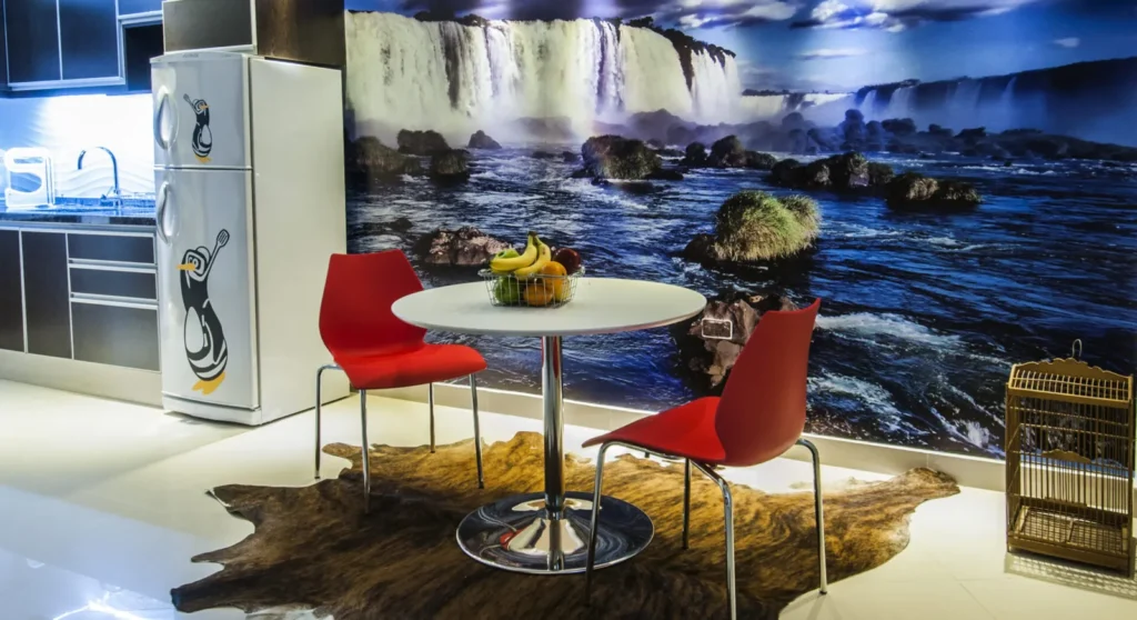 Comedor con mesa redonda, sillas rojas y mural de cataratas