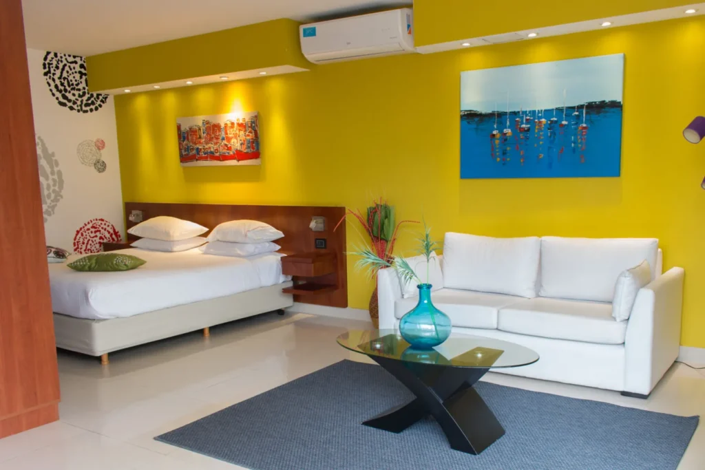Habitación Superior con balcón, pared amarilla y sofá blanco