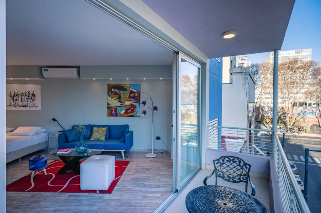 Habitación Superior con balcón, sillón azul y vista a la ciudad
