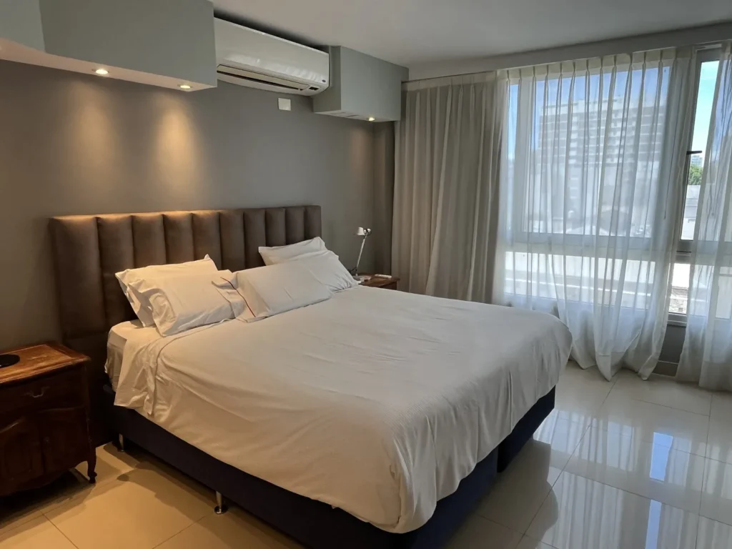 Bed with upholstered headboard and curtains in the Shoshana Suite