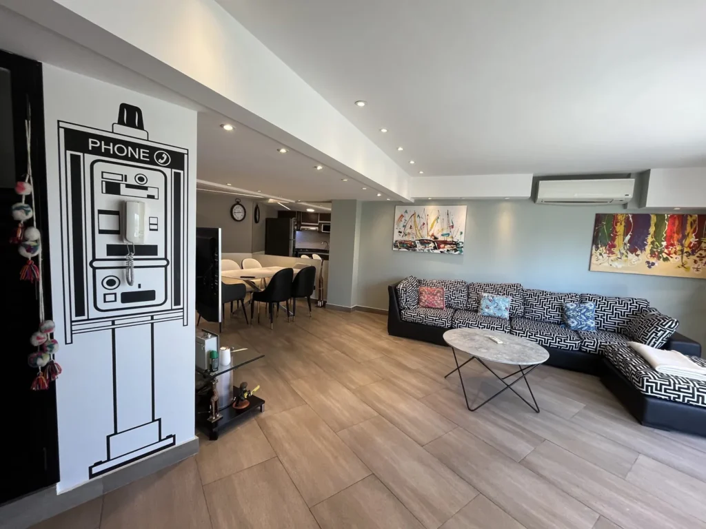 Shoshana Suite living room with corner sofa and dining area behind